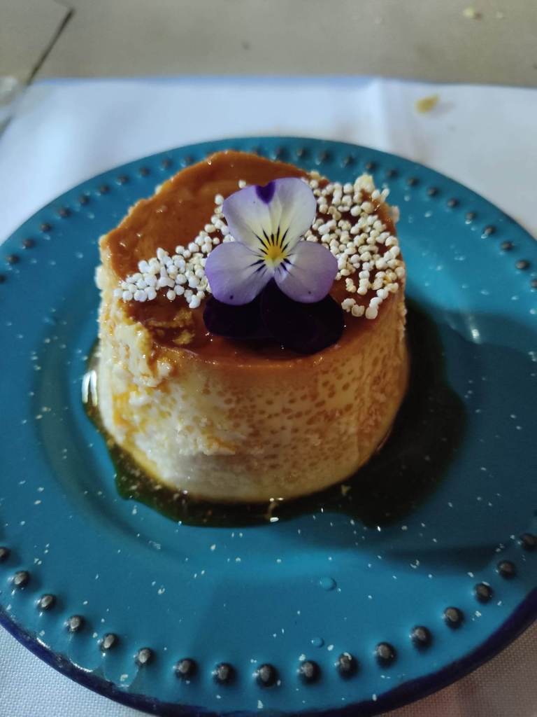 Flan dessert on a plate with a flower on top.