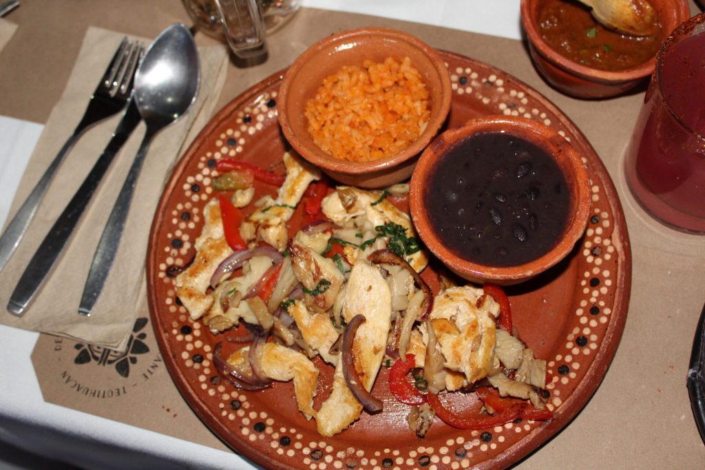 A Plate with chicken fajitas, beans and rice.