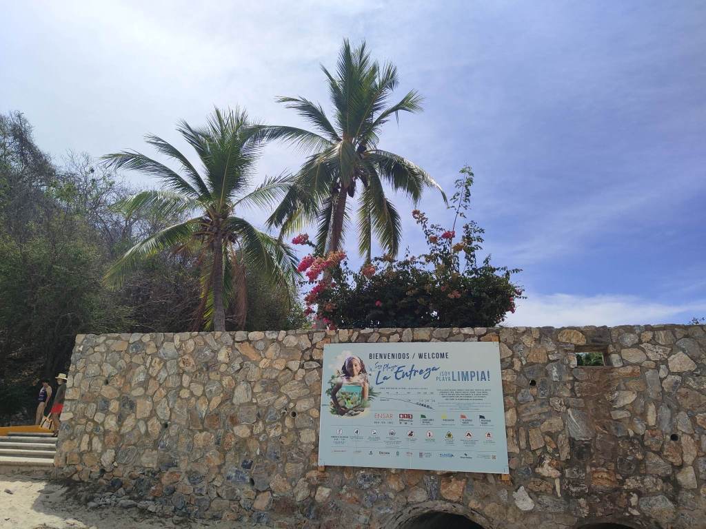 Playa La Entrega sign with palm trees