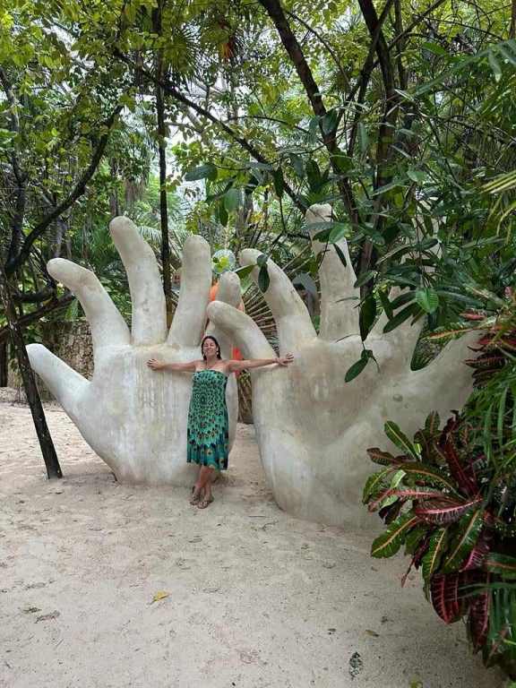 Hand sculpture with the Ven a la Luz sculpture in Tulum